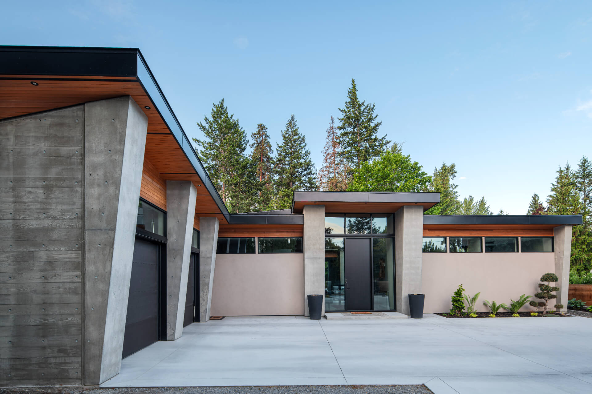 Single-level modern rancher with exposed concrete pillars, cedar soffits and minimalist entry