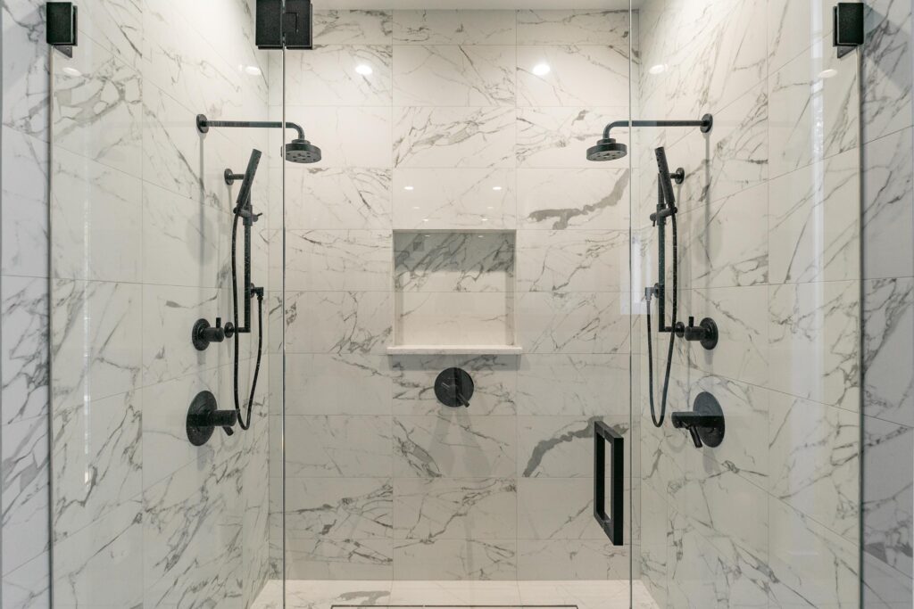 Double walk-in shower with marble-look tile, dual rain heads and matte black hardware