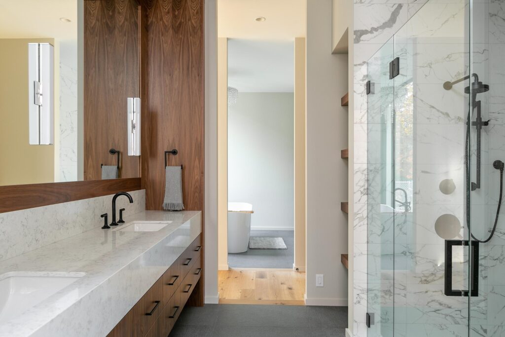 Primary ensuite vanity detail with walnut cabinetry, marble counter and black fixtures