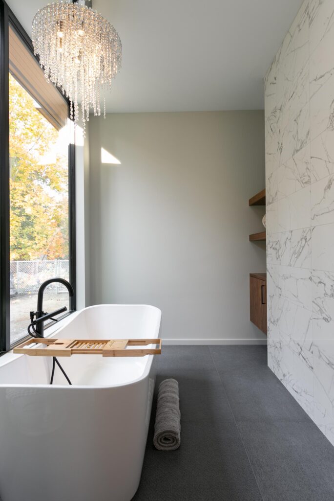 Spa ensuite with freestanding tub, crystal chandelier, black filler and autumn tree views