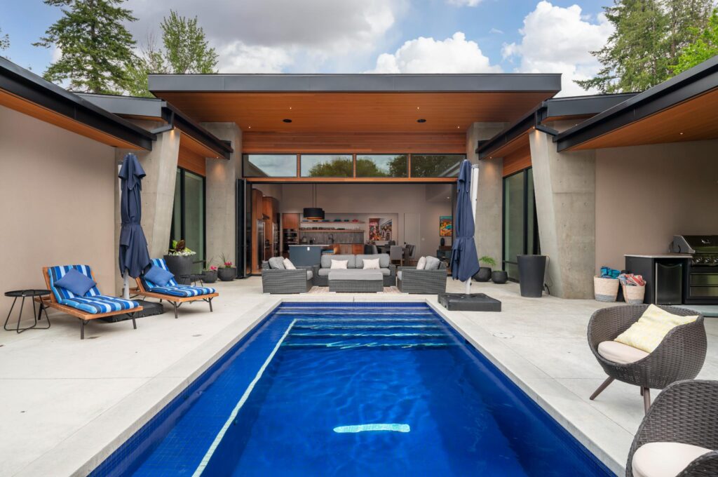 Courtyard pool looking toward open-concept living area with cedar soffits and concrete columns