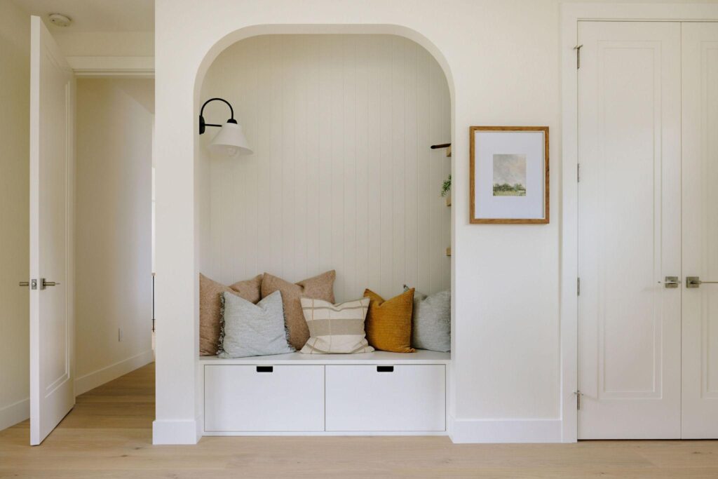 Built-in arched reading nook with shiplap, storage drawers and accent cushions