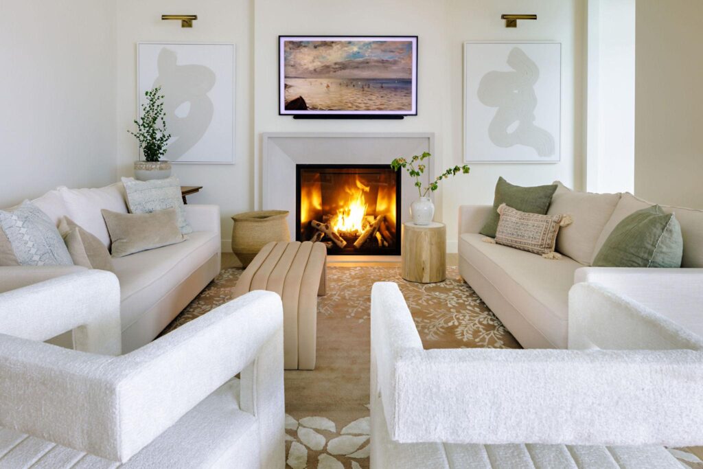 Living room with white concrete fireplace, cream sofas, abstract art and botanical rug
