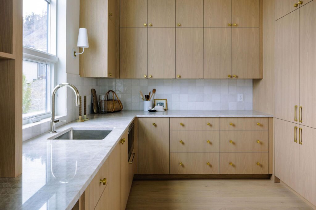 Butler's pantry with floor-to-ceiling oak cabinetry, marble counters and brass hardware