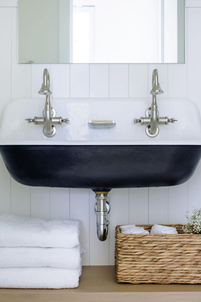 Black farmhouse trough sink with nickel cross-handle faucets and vertical shiplap