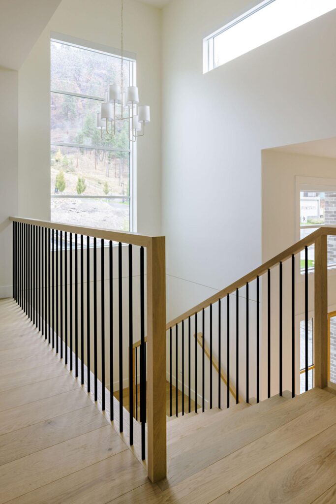 Open staircase with oak handrail, black metal spindles and double-height windows