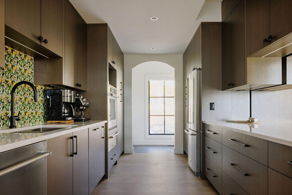 Butler's pantry with oak cabinetry, lemon tile backsplash and arched doorway in a Kelowna custom home