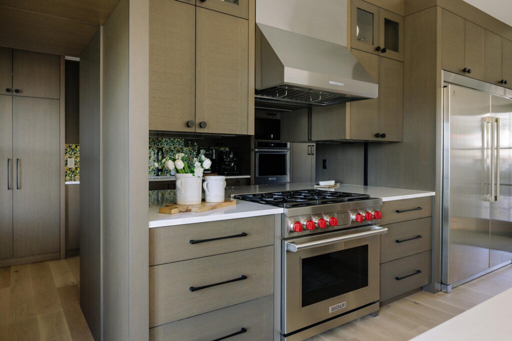 Kitchen range wall with Wolf stove, grey oak cabinetry and lemon tile accent