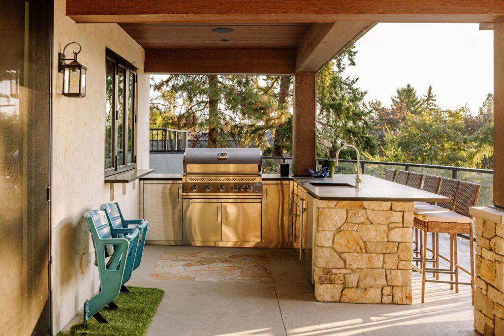 Covered outdoor kitchen with stone island, stainless grill and cedar ceiling