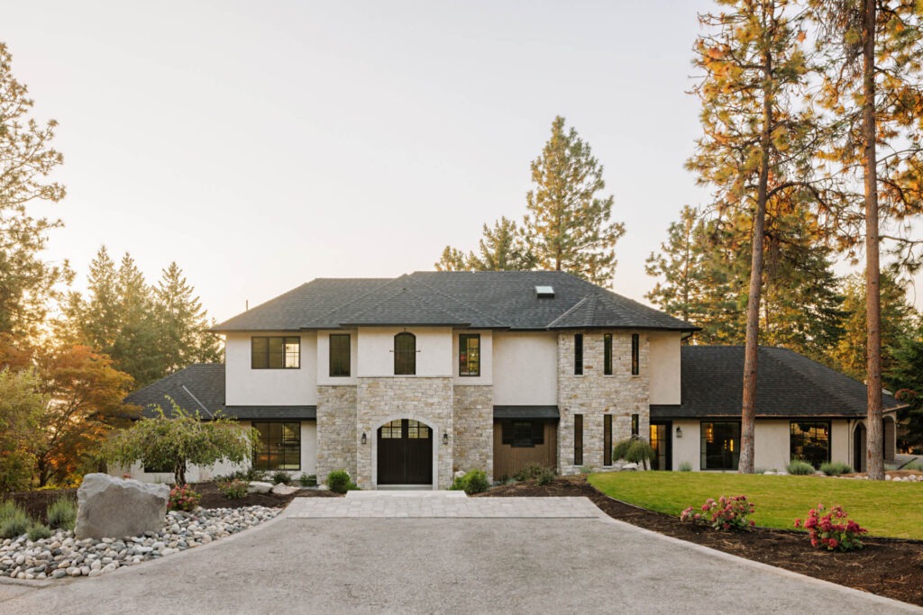 Tuscan-inspired luxury home with stone and stucco exterior surrounded by Okanagan pines